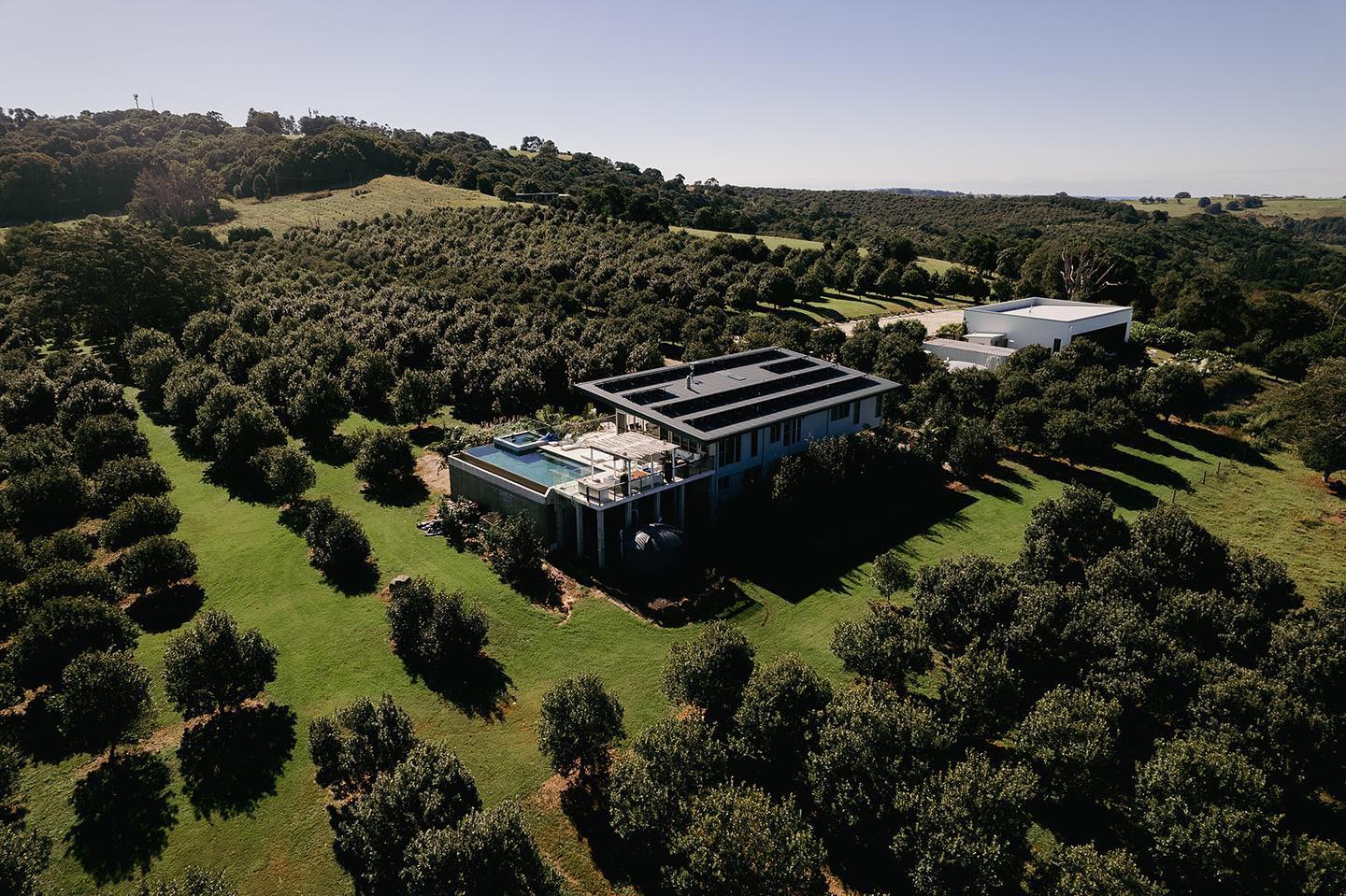 Aerial view of the Villa, infinity pool and Grand Hall surrounded by rows of macadamia trees and open countryside at Tides.