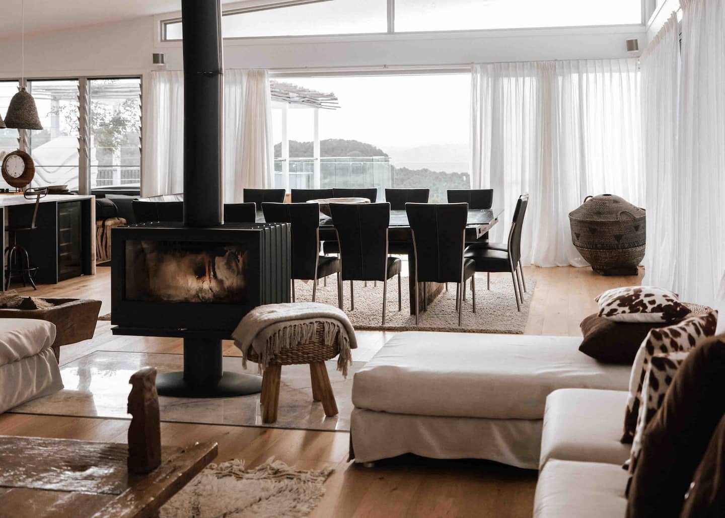 The Villa shared living and dining area with sofas, a freestanding fireplace, dining table and doors to the deck.